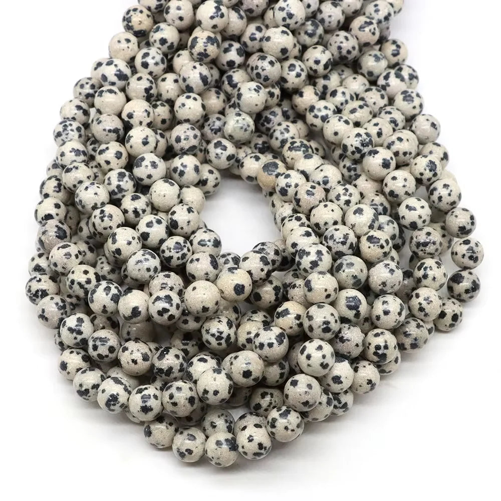 A pile of small, round, speckled natural stone beads for jewelry making in various colors.