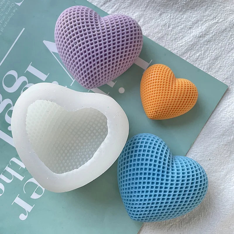 Three silicone heart molds in purple, orange, and blue are displayed on a light green surface.