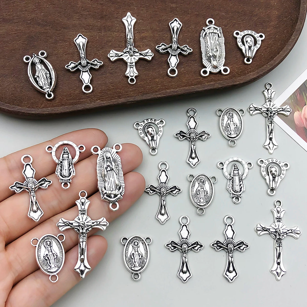 A collection of vintage antique silver cross charms and pendants displayed on a brown wooden tray.