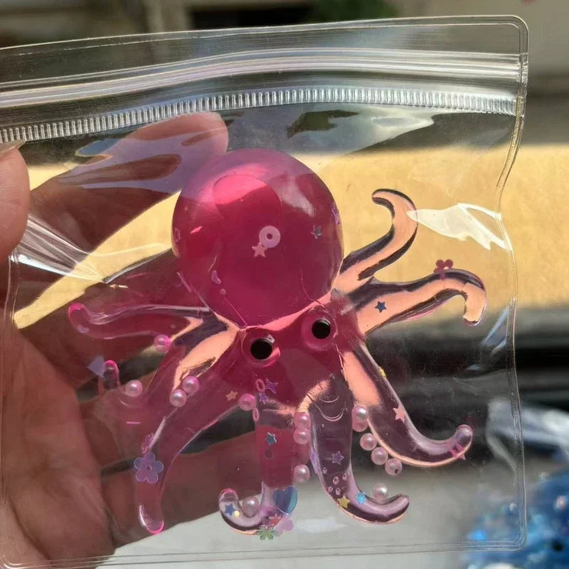 A hand holds a pink stretchable octopus stress ball sensory toy inside clear plastic packaging.
