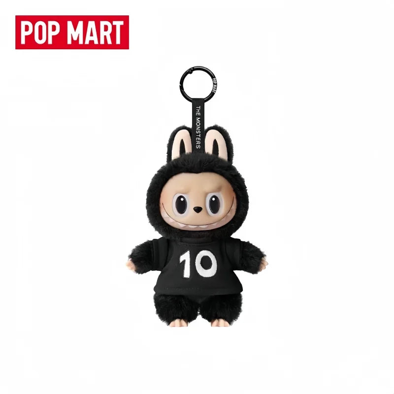 A black plush toy of a monster with large ears and a number 10 on its chest, hanging from a loop.
