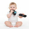 A baby is holding a black silicone teether set with colorful buttons and playing on a white surface.