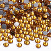 A close-up view of small, faceted glass crystal hot fix rhinestones in various shades of amber and gold.