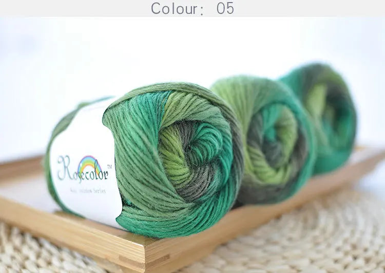 A stack of bright green merino wool yarn skeins in various shades are displayed on a wooden board.