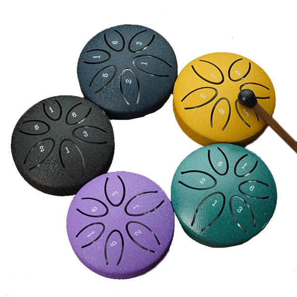 A collection of seven handmade steel tongue drum percussion instruments in various colors including black, yellow, purple, an