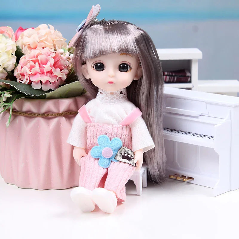 A 17cm articulated princess doll with long gray hair and a pink dress-up outfit sitting next to a white piano.