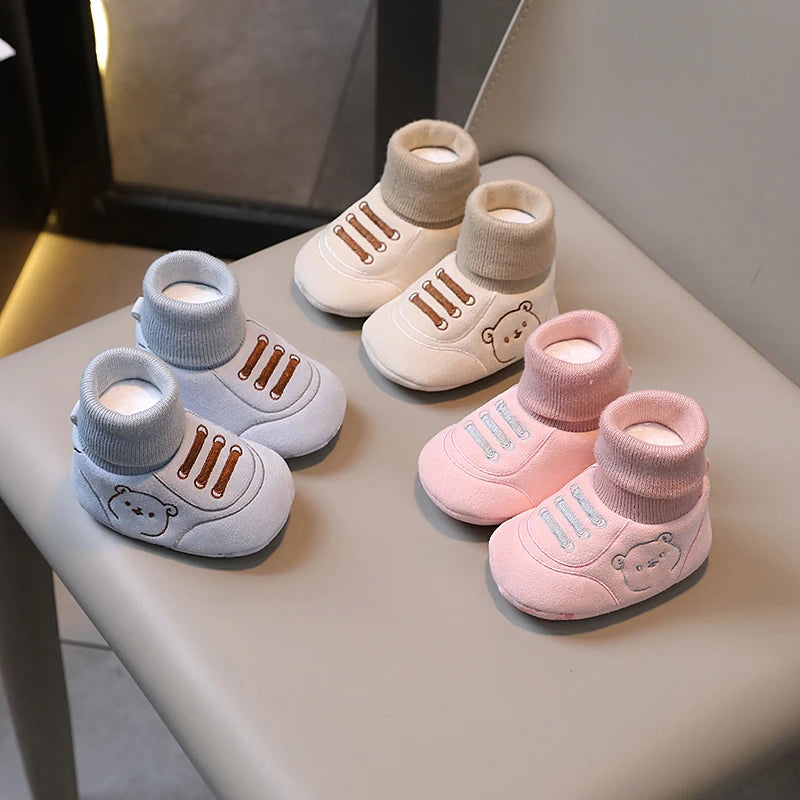 A collection of cozy knit bear booties for baby's first steps in various neutral and pink tones.