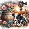 A black and white Highland cow resting in dry grass with flowers and a wooden barrel.