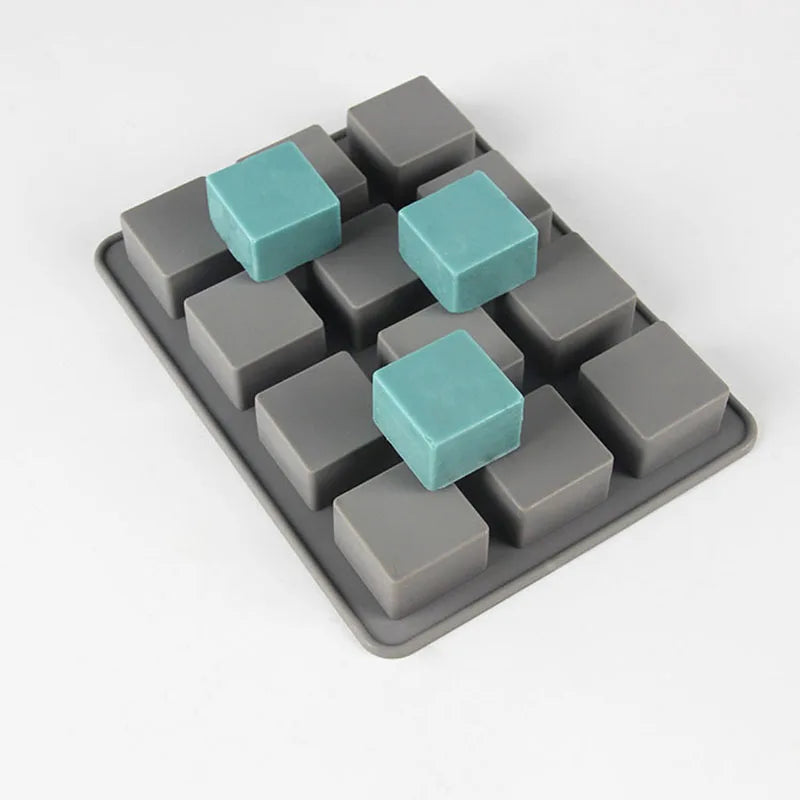 A silicone soap mold with 12 square cavities, featuring a mix of gray and teal silicone pieces.