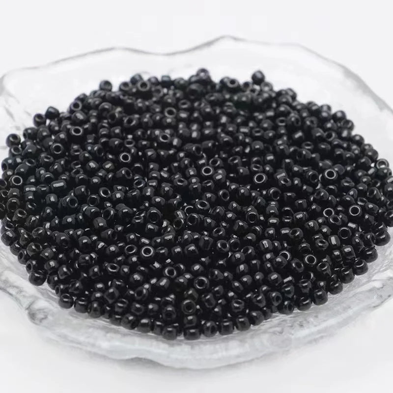 A pile of 2400 glass seed beads in various colors is displayed in a clear dish for jewelry making and crafts.
