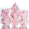 A set of pink resin polyhedral dice shaped like triangles and cubes with floral accents