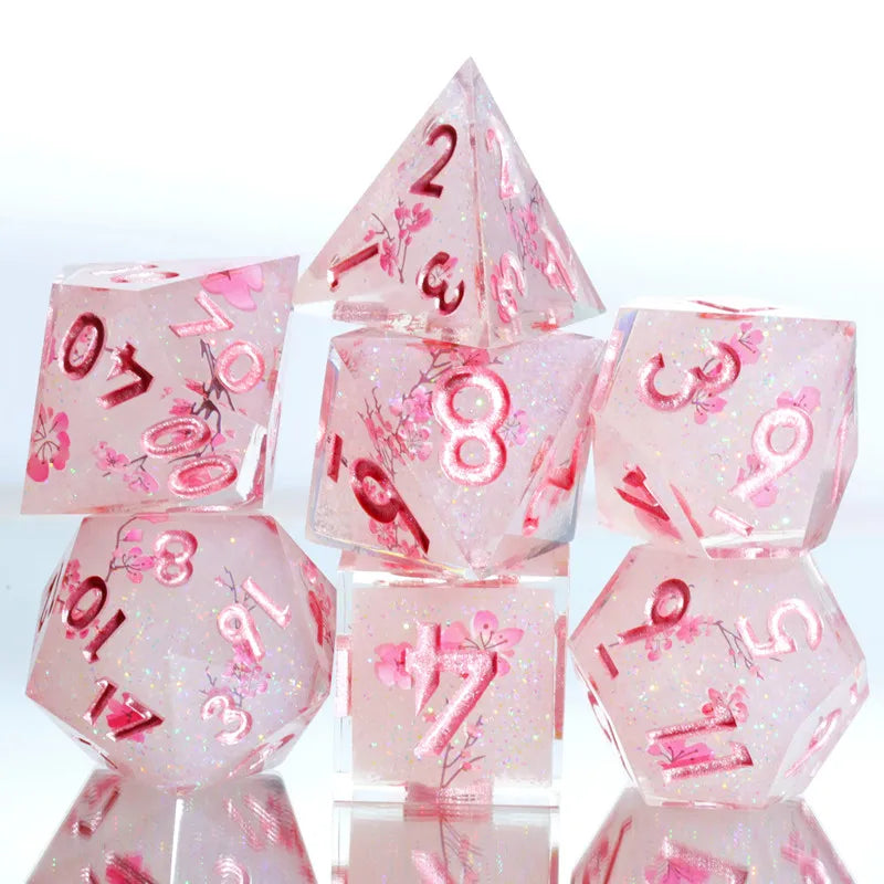 A set of pink resin polyhedral dice shaped like triangles and cubes with floral accents
