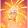 A fluffy, light brown Labubu vinyl plush pendant is shown against a warm orange and pink background with yellow spiky element
