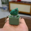 A green duck and frog fidget clicker keychain with a sound and LED light is held in a hand.