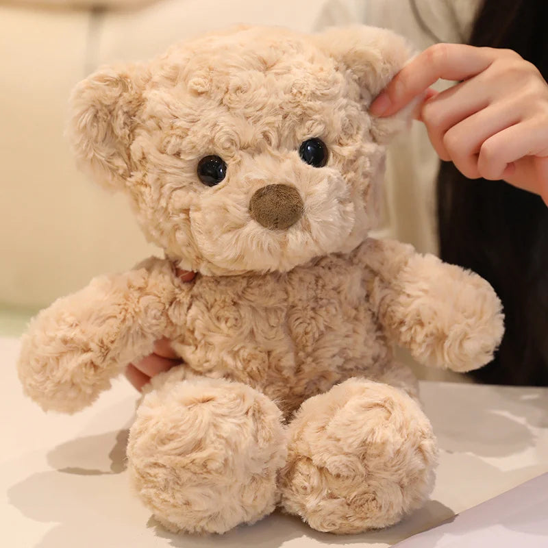 A light beige twisted teddy bear plush toy is being held by a person.