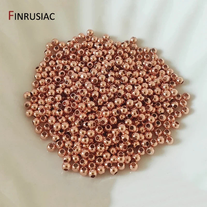 A pile of small, round, rose gold-colored spacer beads for jewelry making.