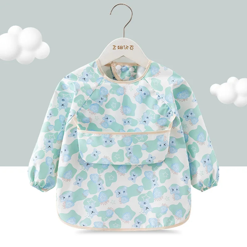 A light blue and green floral patterned toddler feeding bib with long sleeves displayed on a hanger.