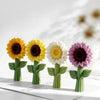 A row of colorful silicone sunflower molds in yellow, white, and purple on a white surface.
