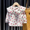 White long-sleeve shirt for a baby girl with a red strawberry print, displayed on a wooden hanger.