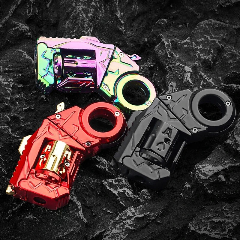 A collection of metal gun-shaped fidget sliders in various colors, including pink, yellow, and black, resting on a dark, text