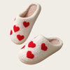 A pair of white plush indoor slippers with red heart accents.