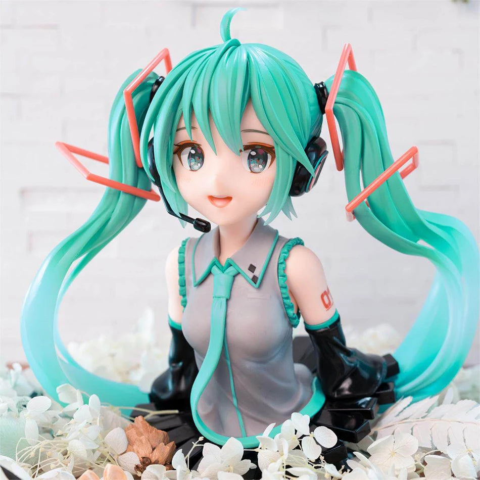A PVC figure of Hatsune Miku with teal hair and headphones, displayed on a white floral arrangement.