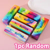 A random assortment of five squishy butter toys in various colors and sizes are displayed on a pink background.