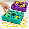 Une main interagit avec un puzzle 3D violet pour enfants, montrant des formes en plastique jaune sur une base verte.