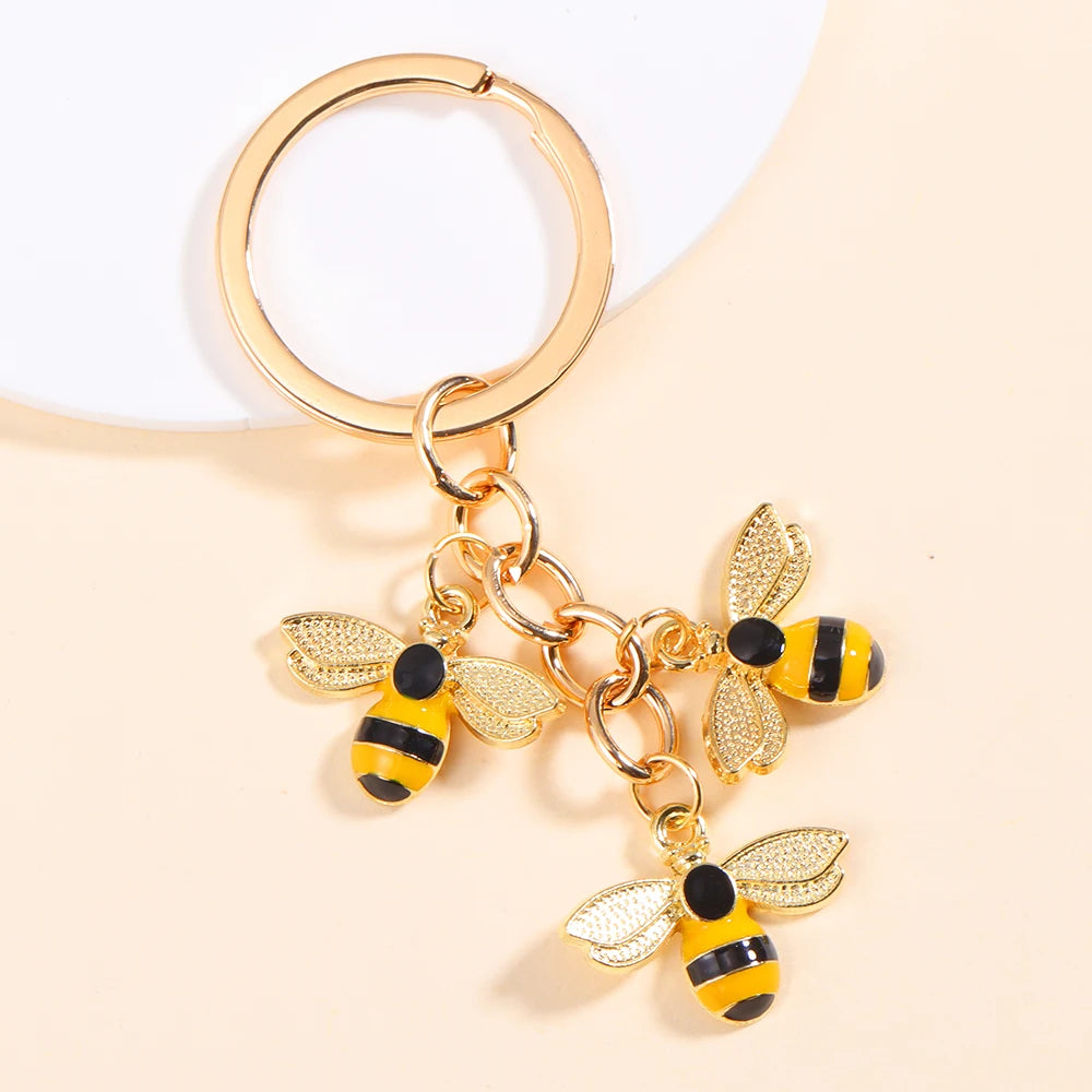 Gold-toned enamel flower keychain featuring a bee design on a circular split ring.