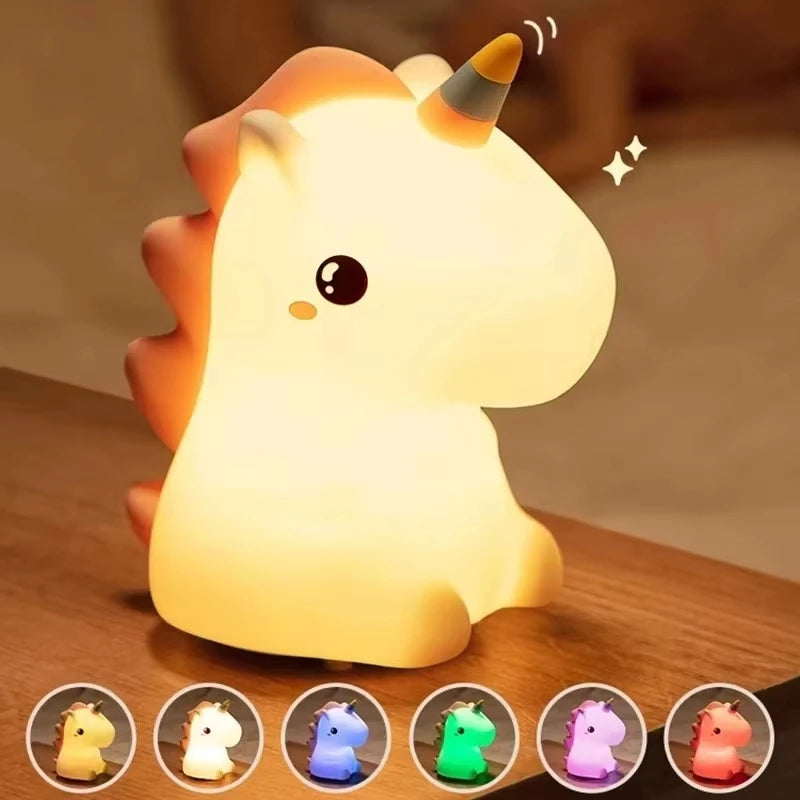 A glowing white unicorn silicone LED night light with a horn and ears resting on a wooden surface.