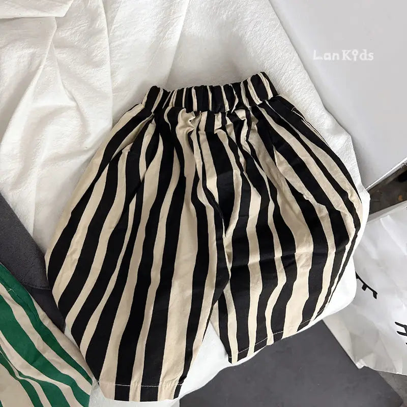 A pair of black and beige striped cotton harem pants laid out on a white surface.