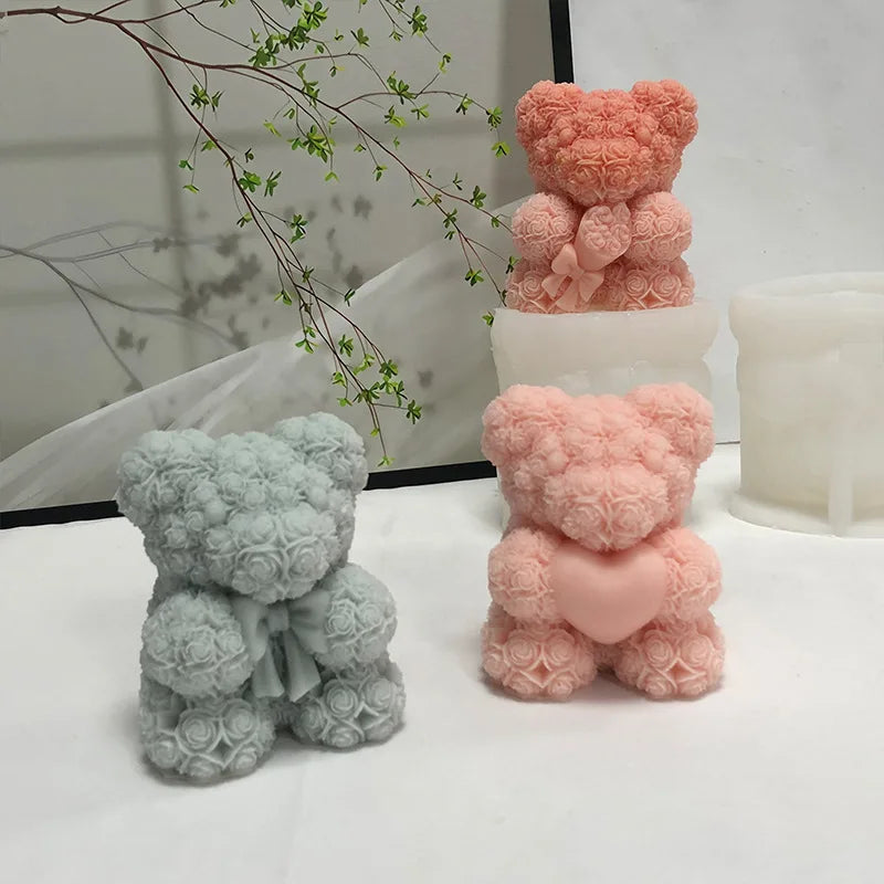 Two silicone bear hug candle molds in pink and light green are displayed on a white surface.
