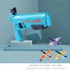 A light blue toy gun and three foam airplanes displayed on a gray surface.