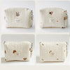 A cream quilted baby diaper caddy organizer with small animal embroidery and attached stroller straps.
