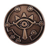 A round, bronze-colored enamel pin featuring a stylized eye design with radiating lines.