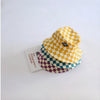 A yellow and purple checkerboard bucket hat is displayed next to a small card.