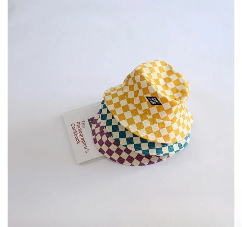 A yellow and purple checkerboard bucket hat is displayed next to a small card.