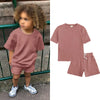A pink kids summer tracksuit set featuring a short sleeve top and matching shorts displayed on a child.