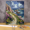 A painting by numbers kit featuring a scenic coastal landscape with cliffs, waves, and colorful wildflowers.