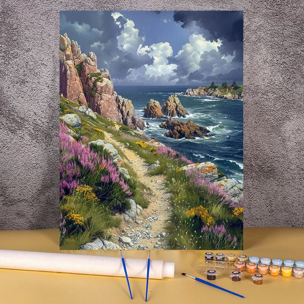 A painting by numbers kit featuring a scenic coastal landscape with cliffs, waves, and colorful wildflowers.