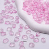 Pink gradient tulip glass beads scattered on a white surface with a white ceramic tool.