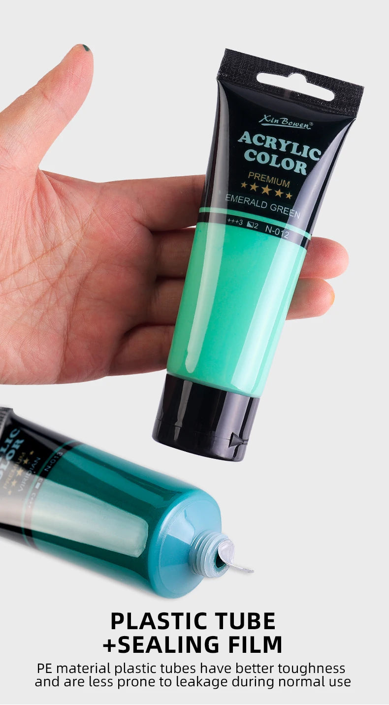A hand holds a tube of emerald green acrylic color paint and an open tube of plastic paint with sealing film.