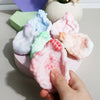 A hand is squeezing a pink squishy stress relief ball with various pastel colored squishies in the background.