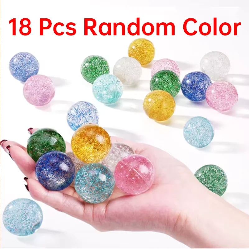 A hand holds various 18 pieces of random color glitter bouncy balls on a white background.