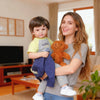 A smiling woman holds a baby in her arms indoors.