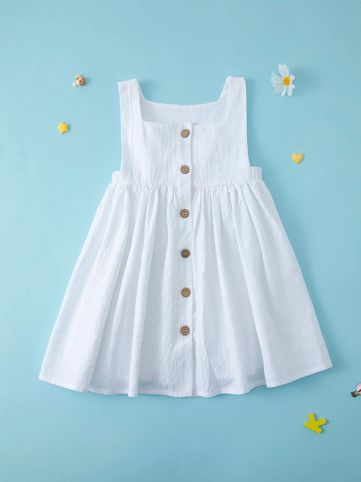 A white summer cotton linen jumper dress for a toddler girl displayed against a light blue background.