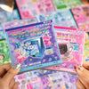 A hand holds a pack of Kawaii Cyber Illusion & Vintage Starlight Die-Cut Stickers featuring various electronic and cute theme