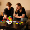 Two children sit at a table playing with colorful plastic blocks for a stacking game.
