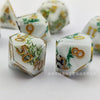 A set of milk white resin dice featuring gold numbers and green foliage with a black kitten design.