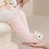 A hand is holding a pink and white coral velvet baby knee-high sock leg warmer.